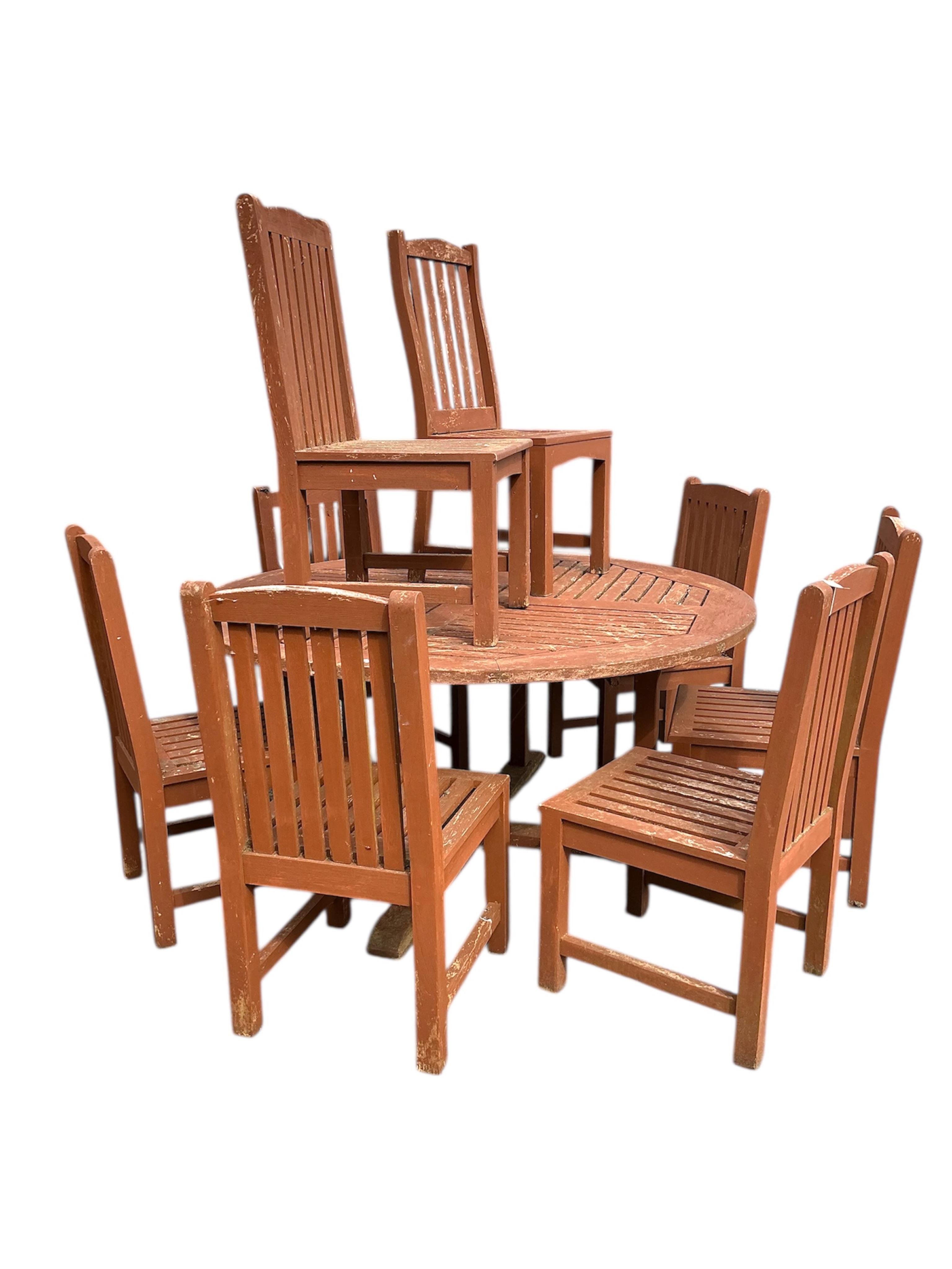 A circular stained teak garden table, diameter 152cm, height 73cm and eight chairs